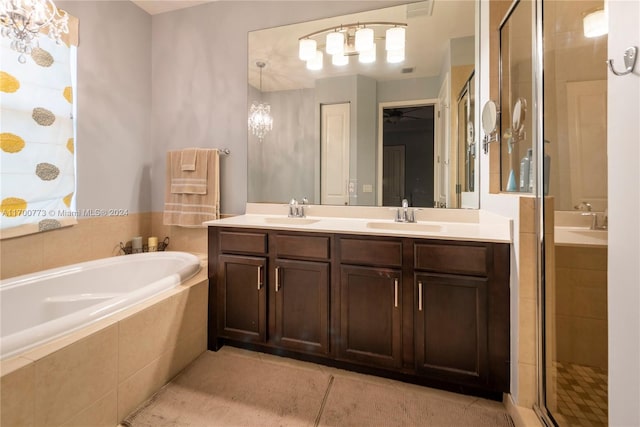 bathroom with tile patterned floors, vanity, independent shower and bath, and a notable chandelier