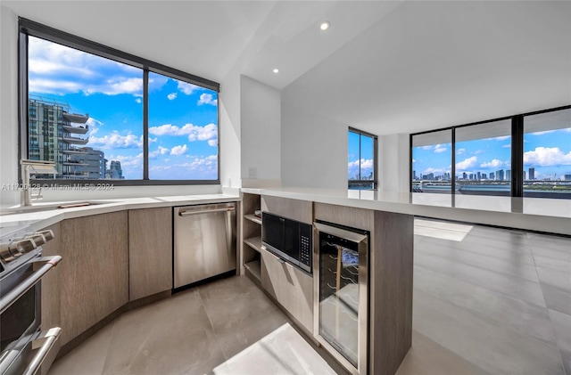 kitchen with floor to ceiling windows, sink, beverage cooler, and appliances with stainless steel finishes