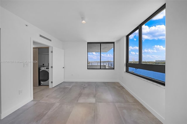 unfurnished room featuring washer / clothes dryer and a wall of windows