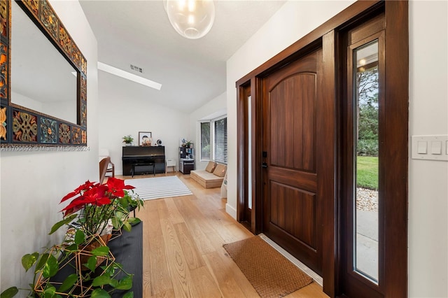 foyer entrance with light wood-type flooring and vaulted ceiling