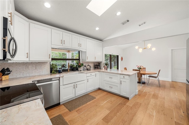 kitchen with lofted ceiling with skylight, sink, light wood-type flooring, appliances with stainless steel finishes, and white cabinetry