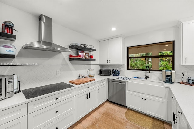 kitchen with wall chimney exhaust hood, stainless steel dishwasher, black electric cooktop, white cabinets, and light wood-type flooring