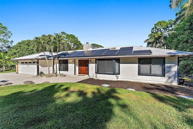 single story home featuring solar panels, a garage, and a front lawn