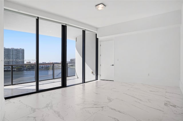 spare room with floor to ceiling windows and a water view