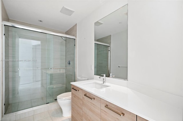 bathroom with tile patterned floors, vanity, toilet, and a shower with shower door