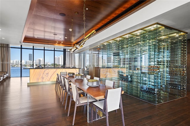 dining area with wood-type flooring, a tray ceiling, a wall of windows, and a water view