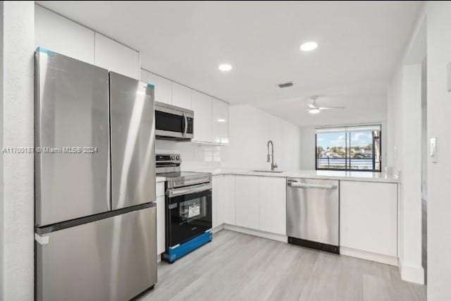 kitchen featuring appliances with stainless steel finishes, light hardwood / wood-style floors, white cabinetry, and sink