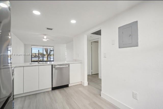 kitchen featuring sink, electric panel, light hardwood / wood-style floors, white cabinets, and appliances with stainless steel finishes