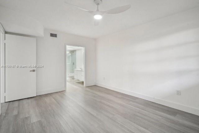 unfurnished bedroom featuring ceiling fan, ensuite bathroom, and wood-type flooring