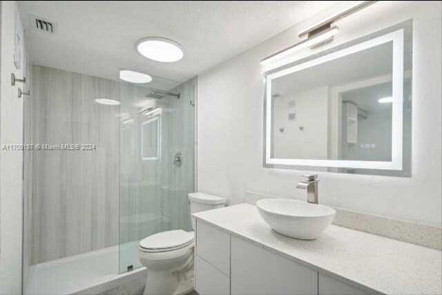 bathroom with a tile shower, vanity, and toilet