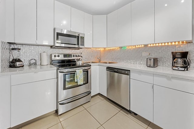 kitchen with white cabinets, decorative backsplash, and stainless steel appliances