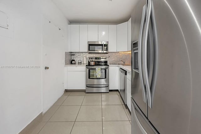 kitchen with backsplash, sink, light tile patterned floors, white cabinetry, and stainless steel appliances