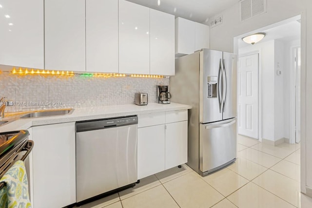 kitchen with white cabinets, appliances with stainless steel finishes, backsplash, and light tile patterned flooring