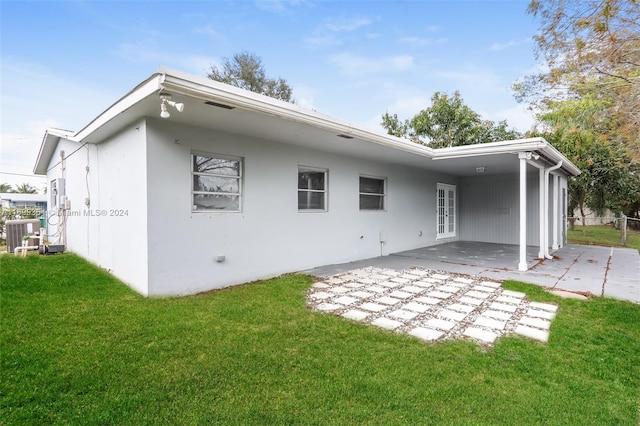 rear view of property with central AC unit, a patio, and a lawn