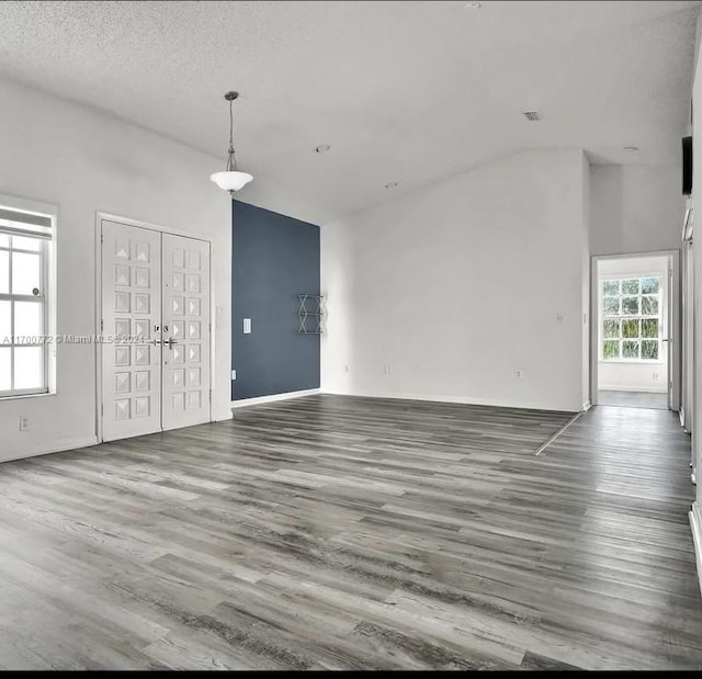 unfurnished room with a textured ceiling, dark hardwood / wood-style floors, and high vaulted ceiling