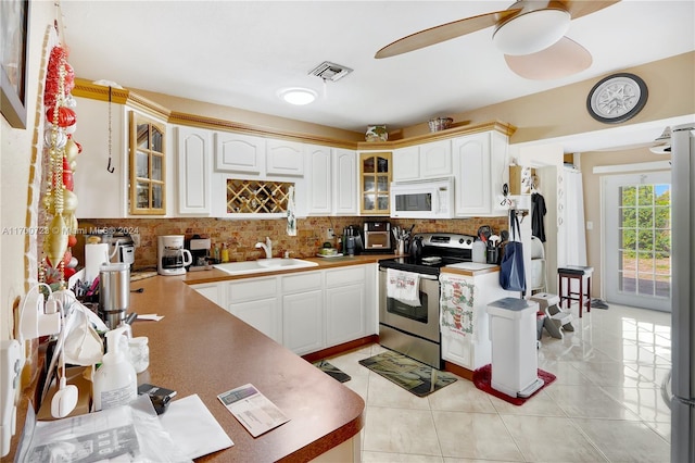 kitchen featuring stainless steel range with electric stovetop, sink, tasteful backsplash, light tile patterned flooring, and white cabinetry