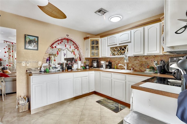 kitchen with white cabinetry, sink, ceiling fan, tasteful backsplash, and light tile patterned flooring