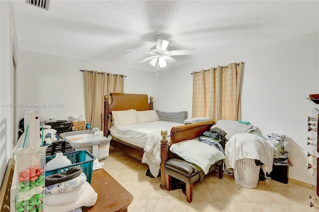 bedroom with ceiling fan, light tile patterned floors, and a textured ceiling