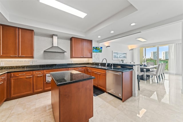 kitchen with dishwasher, sink, wall chimney range hood, a raised ceiling, and a kitchen island