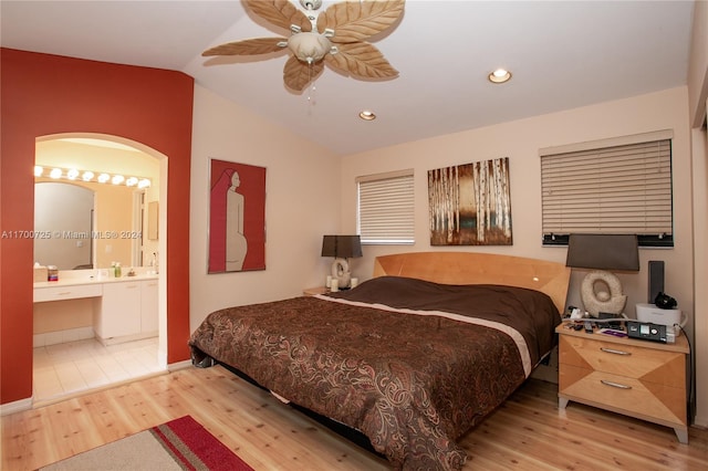 bedroom featuring ceiling fan, light hardwood / wood-style floors, lofted ceiling, and connected bathroom