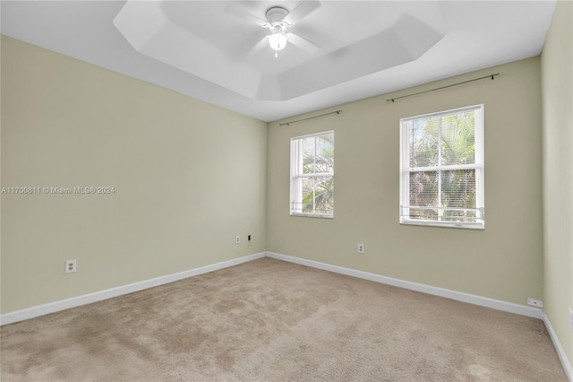 carpeted spare room featuring a raised ceiling and ceiling fan