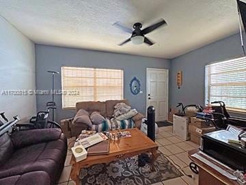 living room featuring ceiling fan, light tile patterned flooring, and a textured ceiling