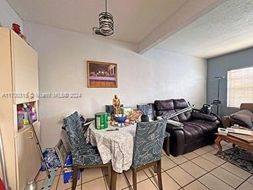 tiled dining area featuring beamed ceiling