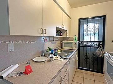 kitchen with white cabinetry, stainless steel range, light tile patterned floors, and sink