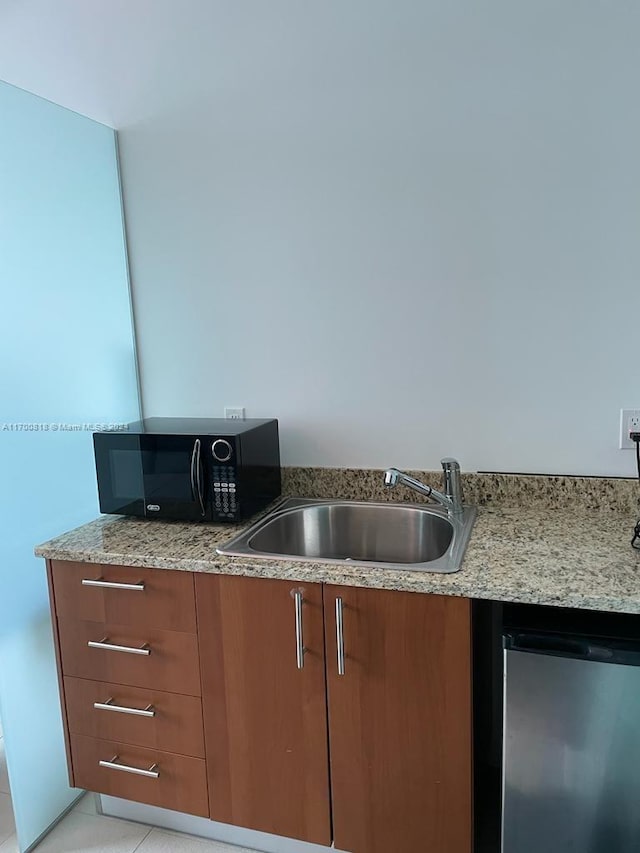 kitchen featuring light tile patterned flooring, stainless steel dishwasher, light stone countertops, and sink