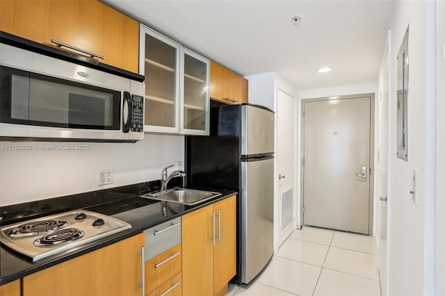 kitchen featuring sink, stainless steel appliances, dark stone countertops, and light tile patterned floors