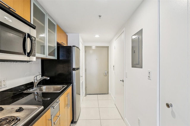 kitchen with sink, electric panel, light tile patterned floors, stovetop, and dark stone countertops