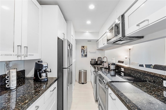 kitchen featuring dark stone counters, sink, white cabinets, and stainless steel appliances