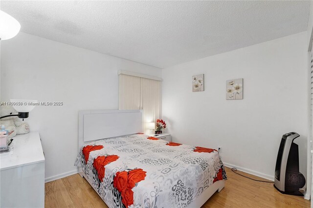 5236 NE 6th Ave Unit G25, Oakland Park, FL 33334 - bedroom featuring light wood finished floors, a textured ceiling, and baseboards