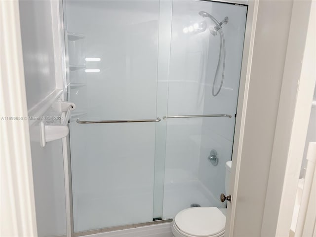 bathroom featuring toilet and a shower with door