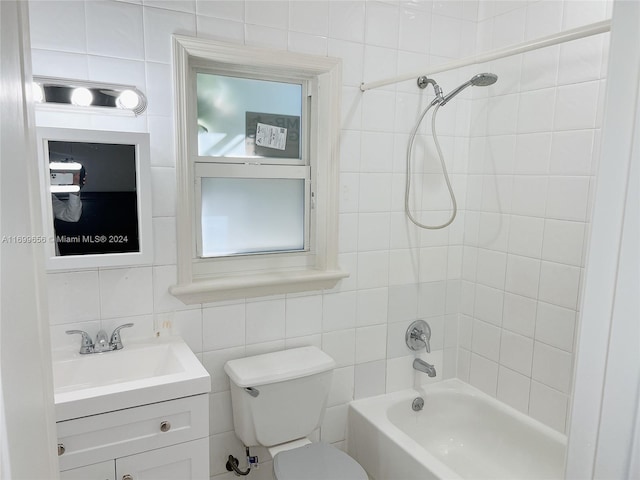 full bathroom with vanity, decorative backsplash, tiled shower / bath combo, toilet, and tile walls