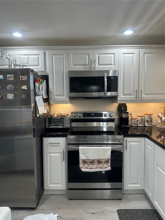 kitchen with appliances with stainless steel finishes, light hardwood / wood-style floors, and white cabinetry