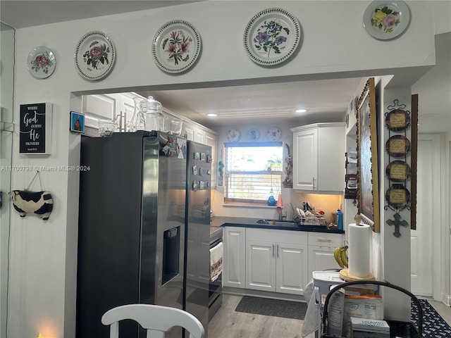 kitchen featuring backsplash, black fridge, sink, light hardwood / wood-style flooring, and white cabinetry