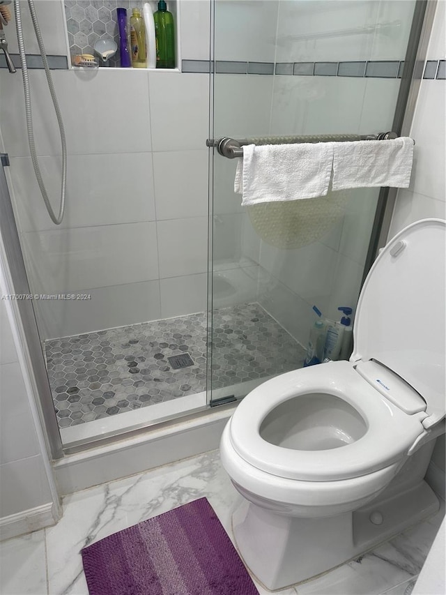 bathroom featuring toilet and a shower with shower door