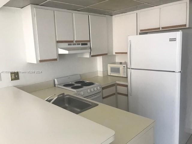 kitchen with sink, a drop ceiling, kitchen peninsula, white appliances, and white cabinets