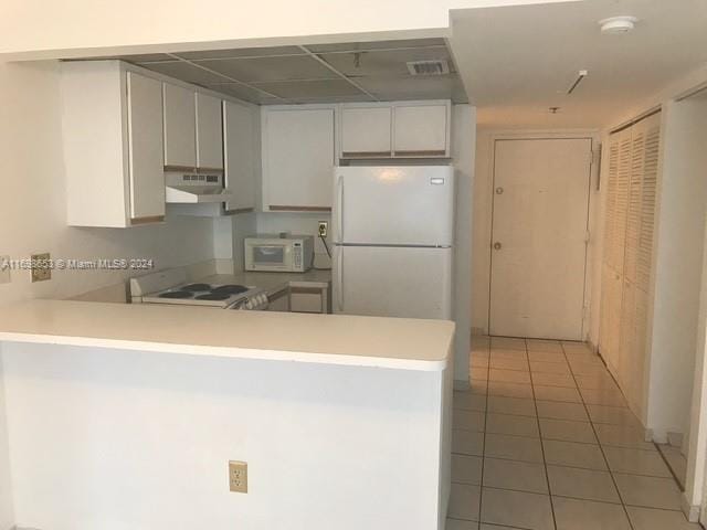 kitchen featuring kitchen peninsula, tile patterned flooring, white cabinets, and white appliances