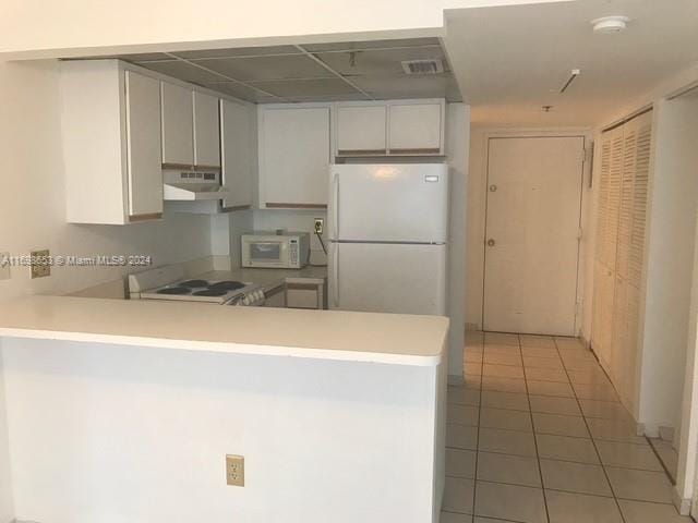 540 Brickell Key Dr Unit 830, Miami, FL 33131 - kitchen with under cabinet range hood, white appliances, a peninsula, light tile patterned flooring, and light countertops