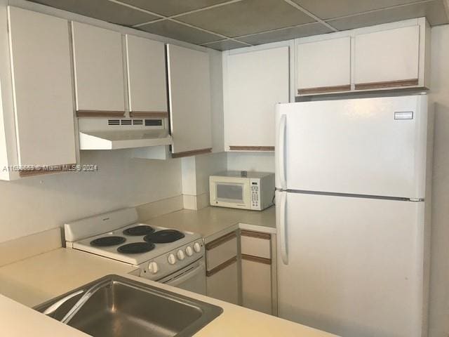 kitchen with a drop ceiling, white cabinetry, white appliances, and sink