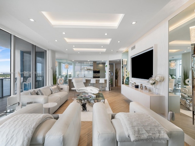 living room featuring floor to ceiling windows, a tray ceiling, and light hardwood / wood-style flooring