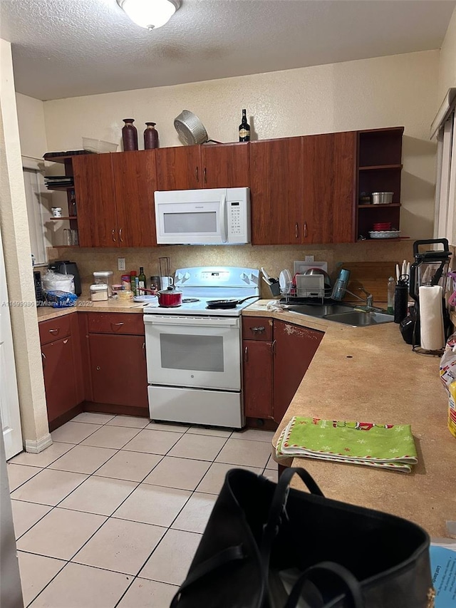 kitchen with sink, kitchen peninsula, a textured ceiling, white appliances, and light tile patterned floors