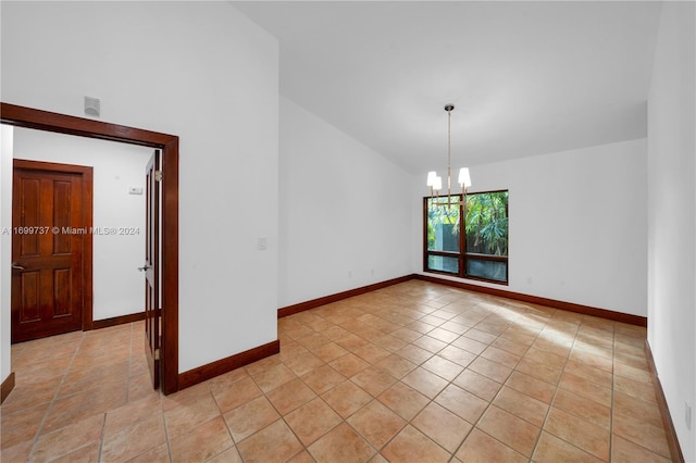 tiled empty room with lofted ceiling and an inviting chandelier