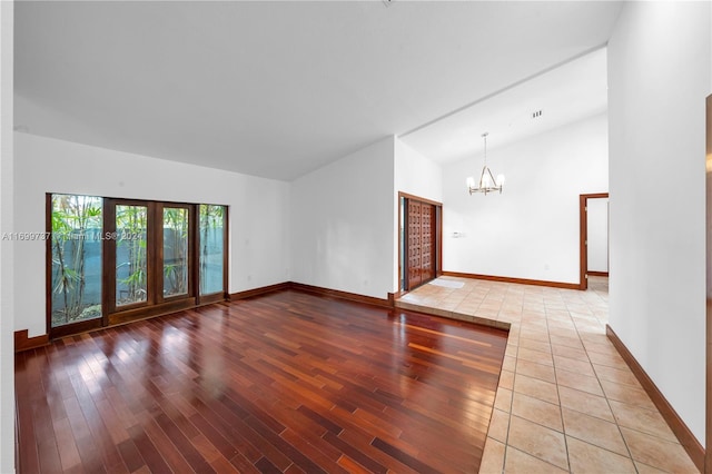 unfurnished room with a chandelier, hardwood / wood-style floors, and vaulted ceiling