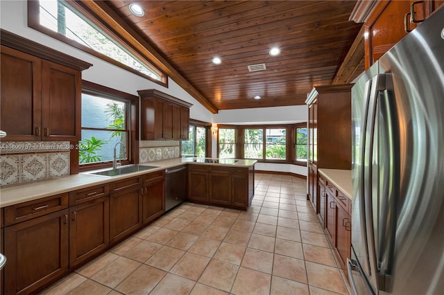 kitchen featuring lofted ceiling, sink, decorative backsplash, appliances with stainless steel finishes, and kitchen peninsula