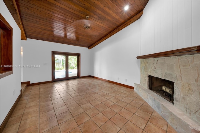 unfurnished living room with french doors, a stone fireplace, vaulted ceiling, light tile patterned floors, and wood ceiling