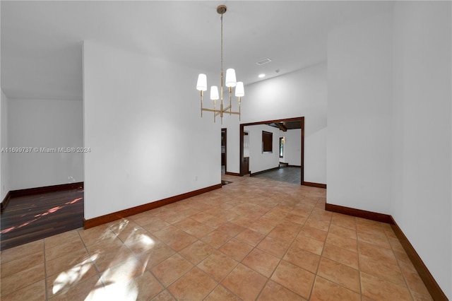 tiled empty room with an inviting chandelier