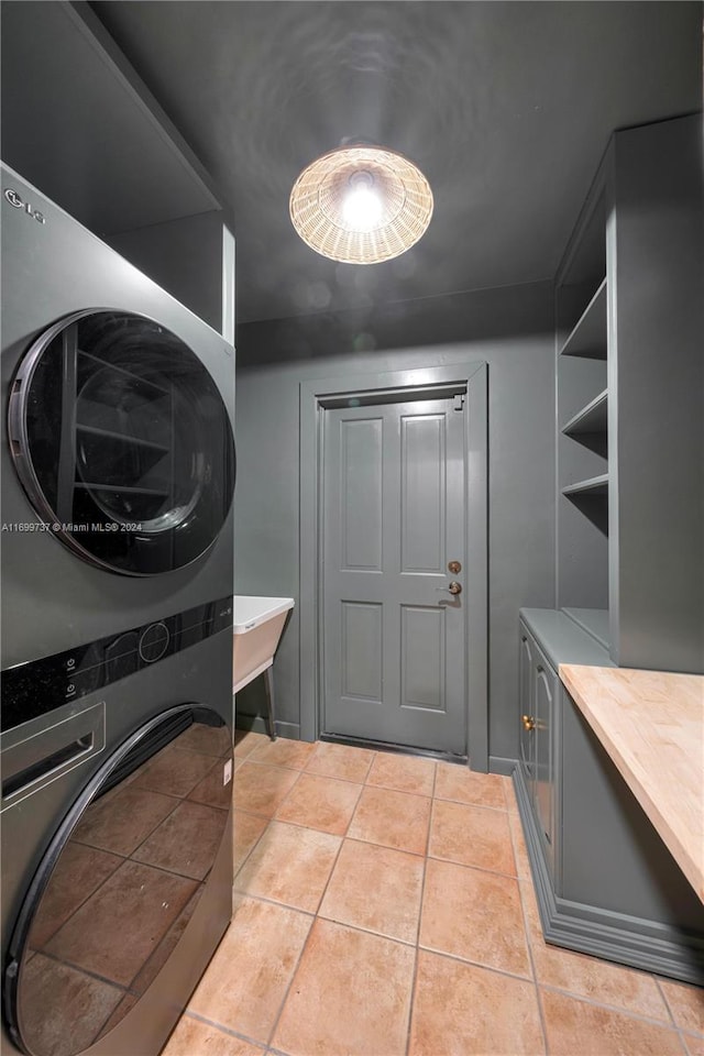 laundry room featuring light tile patterned floors and stacked washing maching and dryer